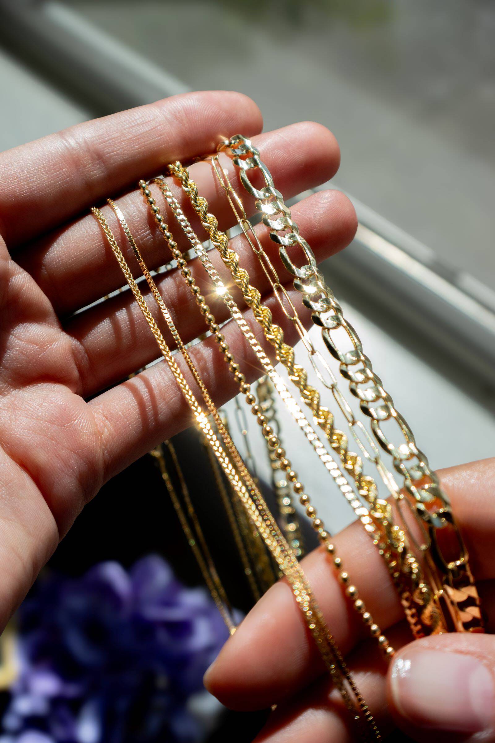 Several gold chain draped over a woman's fingers